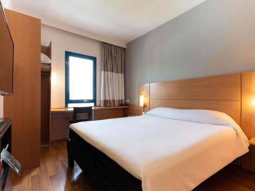 a hotel room with a large bed and a window at Ibis Fes in Fez