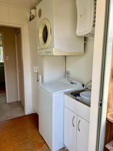 a small kitchen with a washing machine and a sink at Secluded Bush Retreat in Hikuai