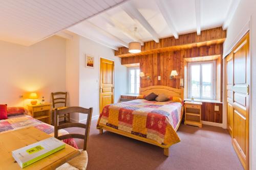 a bedroom with two beds and a desk and a table at Hôtel Restaurant Au Pont de Raffiny in Saint-Romain