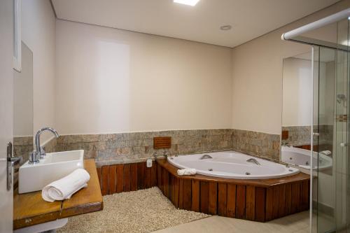a bathroom with a tub and a sink and a shower at ARAÝ Pousada in Campos do Jordão