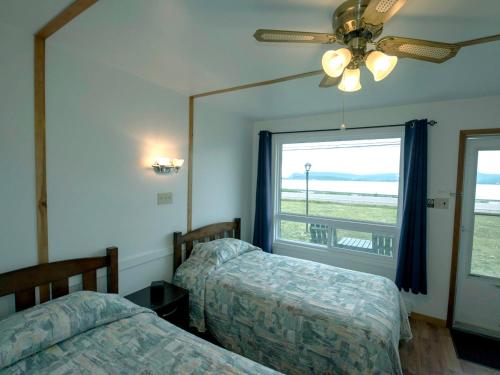 two beds in a room with a window and a ceiling fan at Sea Breeze Motel in Ingonish