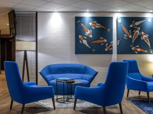 ein Wartezimmer mit blauen Stühlen und einem Gemälde von Fischen in der Unterkunft Mercure Vannes Le Port in Vannes
