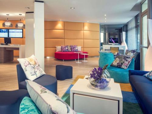 a living room with blue couches and a red couch at Mercure Nice Centre Grimaldi in Nice