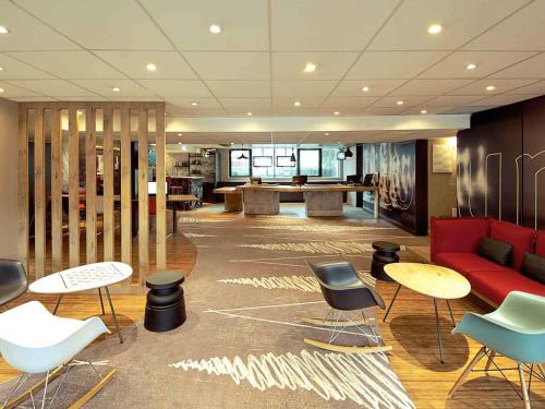 a lobby with a red couch and tables and chairs at ibis Paris Saint-Denis Stade Sud in Saint-Denis