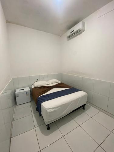 a small white room with a bed in it at Pousada JM in Salgueiro
