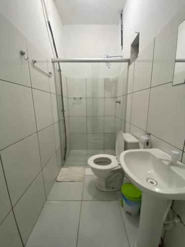 a white bathroom with a toilet and a sink at Pousada JM in Salgueiro