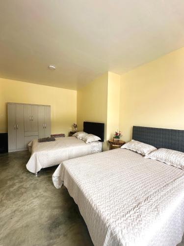 two beds in a room with white sheets at Munay Wasy Carhuaz in Carhuaz