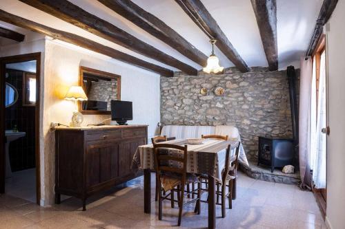a dining room with a table and a stone wall at Casa Baró in Tornafort