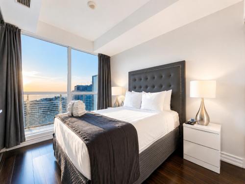 a bedroom with a large bed and a large window at Altitude Suites on Yonge - Downtown Toronto Short Walk to SickKids, TMU & Eaton Centre in Toronto