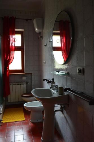 a bathroom with a sink and a mirror and a toilet at B&B Tramonti sull'Adriatico in Muggia