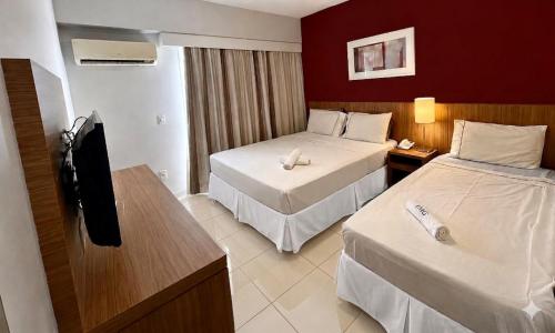 a hotel room with two beds and a television at Flat & Suite Premium - Rio Centro - Barra - Farmasi Arena in Rio de Janeiro