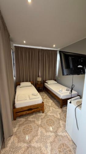 a room with two beds and a flat screen tv at Dhoma Elena in Dhërmi