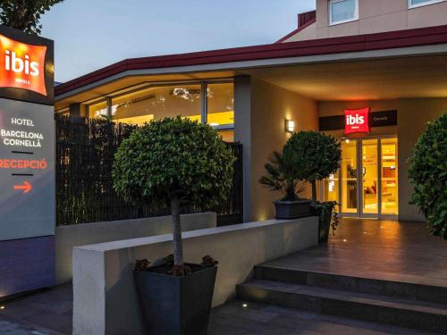 a building with two potted trees in front of it at Ibis Cornella in Cornellà de Llobregat