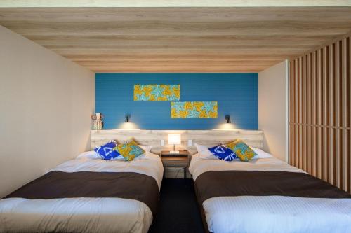 two beds in a room with a blue wall at THE SHIKAKA Hotel&Resort BUDOUNOKI in Itoshima