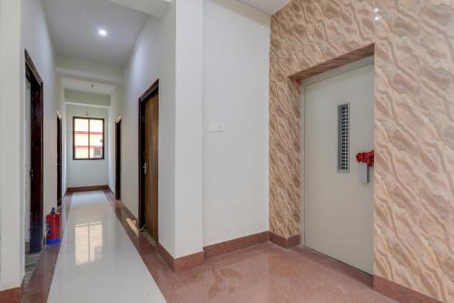 a hallway with white walls and a wooden door at Hotel O White House in Patna