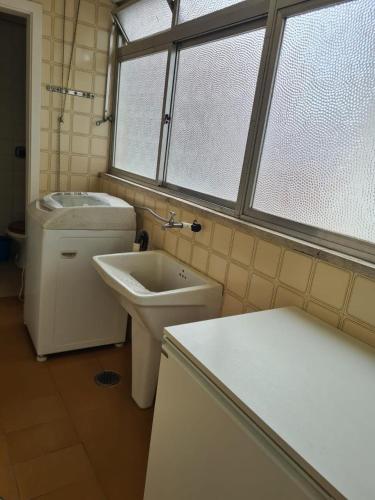 a bathroom with a sink and a toilet and a window at Ap Central 3 quartos com elevador e garagem in Pelotas