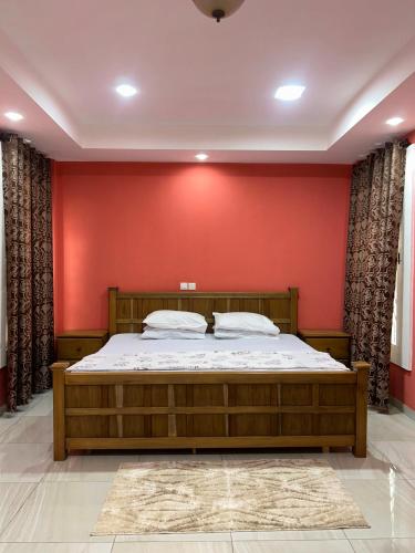 a bedroom with a bed with a red wall at Villa Char in Accra