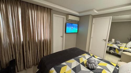 a bedroom with a bed and a tv on the wall at Horto da Barra - Apartamento à Beira Mar in Barra dos Coqueiros