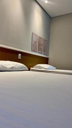 a bedroom with two beds and two paintings on the wall at Pousada Bella in Vitória da Conquista