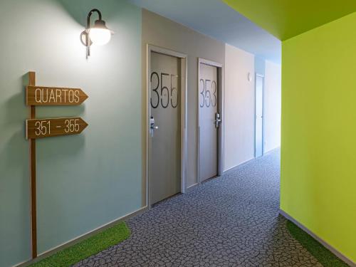a hallway with two doors and a sign that reads baths at ibis Styles Curitiba Centro Civico in Curitiba