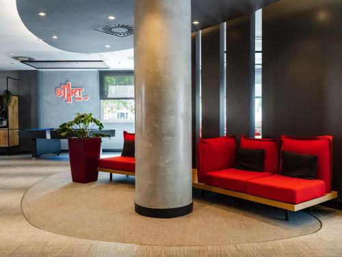 a lobby with a red couch and a pole at Ibis Barcelona Castelldefels in Castelldefels