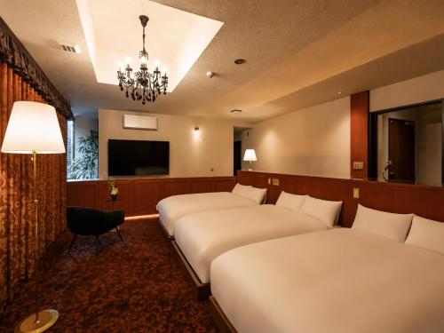 a hotel room with three beds and a chandelier at ホテル寺町亘hotel teramachi watari in Matsue