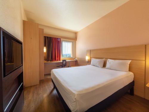 a hotel room with a bed and a television at ibis Manaus Distrito Industrial in Manaus