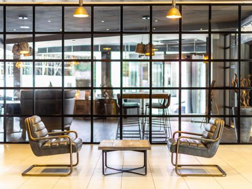 a lobby with chairs and a table and windows at Novotel Leeds Centre in Leeds
