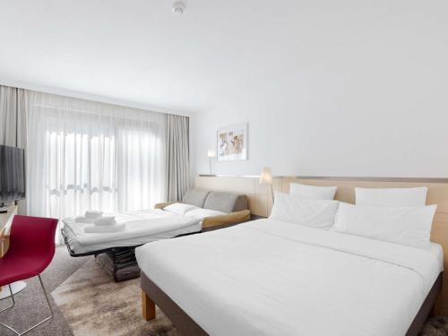 a hotel room with a large white bed and a couch at Novotel Berlin Mitte in Berlin