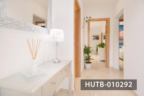 Cette chambre blanche dispose d'une table avec une lampe et d'un couloir. dans l'établissement Apartamento Roca Mar, à Sitges