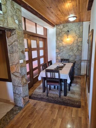 a dining room with a table and a stone wall at Family Apartments in Žabljak