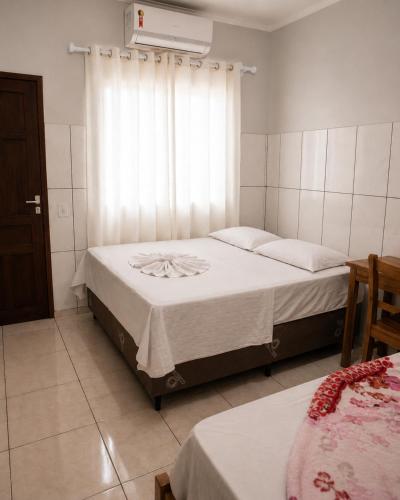a bedroom with two beds and a window at Caliani Hotel in Espigão dʼOeste