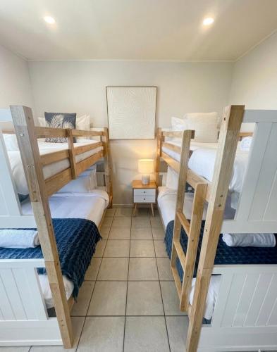 a room with four bunk beds in it at Beach Days, Ocean Rooftop & Spa - Sleeps 8 in Marcoola