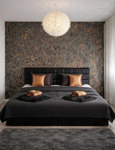 a bedroom with a large black bed with a chandelier at Guest House Eden in Bihać