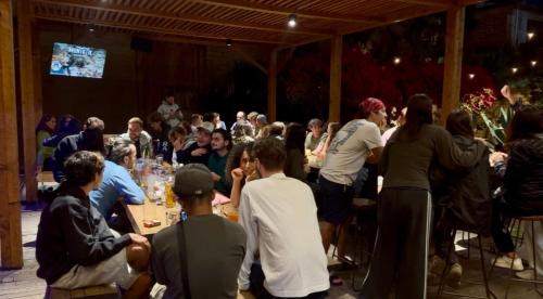 a group of people sitting at tables at a party at Puerta Vieja Hostel in San Cristóbal de Las Casas