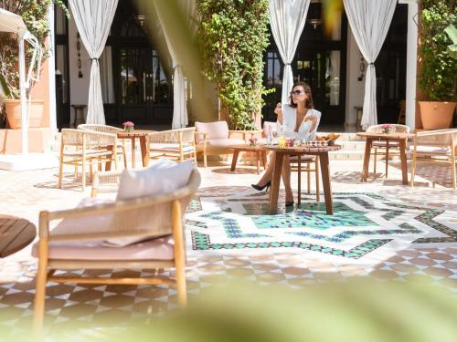 a woman sitting at a table talking on a cell phone at Sofitel Marrakech Palais Impérial & Spa in Marrakesh