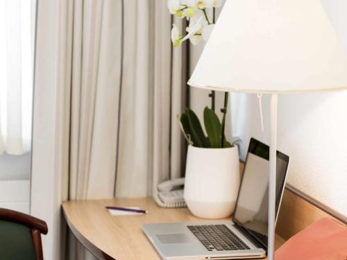 a desk with a laptop and a lamp on it at Résidence Studio Genève Centre in Geneva