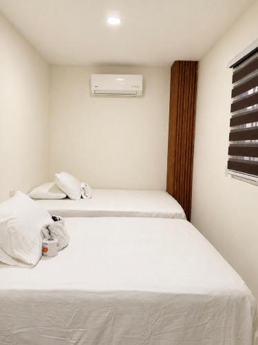 a bedroom with two beds with white sheets at Hotel Castillo in San Pedro Sula