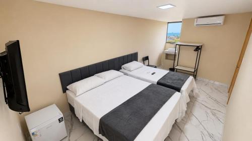 a bedroom with two beds and a flat screen tv at Made Hotel in São Luís