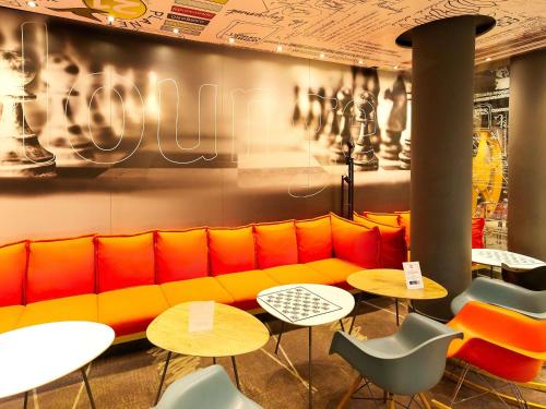 ein Restaurant mit einem gelben Sofa und Tischen in der Unterkunft ibis Berlin City Potsdamer Platz in Berlin