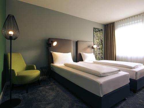 a hotel room with two beds and a chair at Mercure Hotel Plaza Essen in Essen