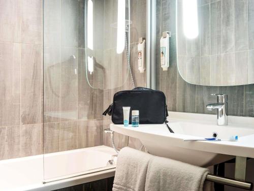 a bathroom with a sink and a bag on the counter at Ibis Orly Chevilly Tram 7 in Chevilly-Larue