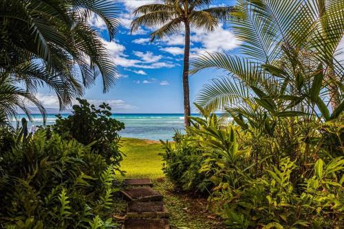 a path leading to a beach with palm trees and the ocean at Hale Mahina A102 in Kahana