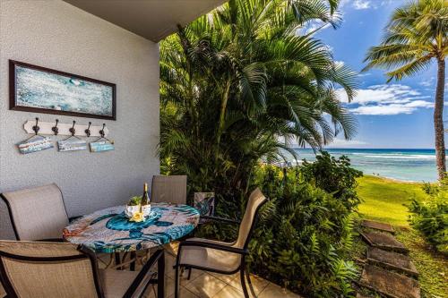 a patio with a table and chairs and the ocean at Hale Mahina A102 in Kahana