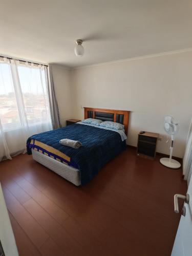 a bedroom with a bed and a window with a fan at Hermoso y cómodo departamento en edificio in Calama