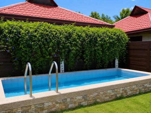 a swimming pool in front of a hedge at Villa Flora Bella Yellow Bell in Dauis