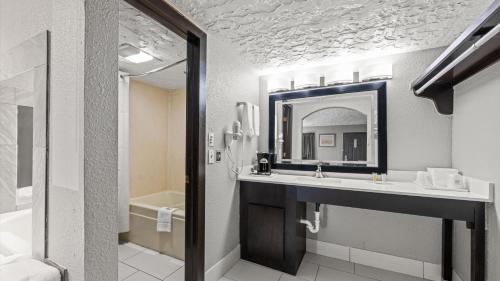 a bathroom with a sink and a mirror and a tub at Super 8 by Wyndham Norman West OK in Norman