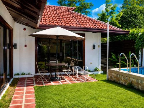 a patio with an umbrella and a table and chairs at Villa Flora Bella Yellow Bell in Dauis