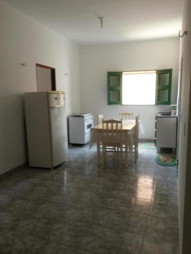 a room with a kitchen with a table and a refrigerator at Suíte central Pousada in Jijoca de Jericoacoara