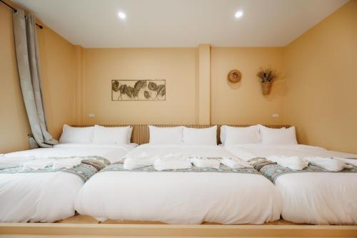 a row of white beds in a room at เพลาวิลล่า in Langu